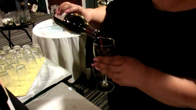 A person pouring red wine into a glass at a table.