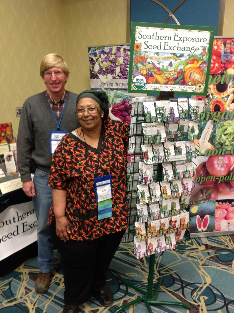Two people standing near a seed exchange display at an event.