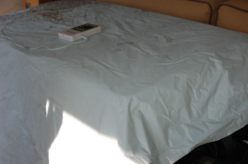 A wrinkled light gray bedsheet with a white remote control on top.