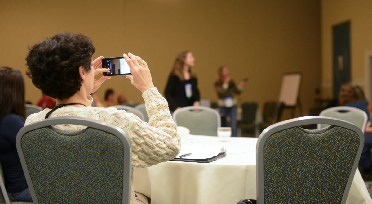 Person taking a photo at a conference or meeting.