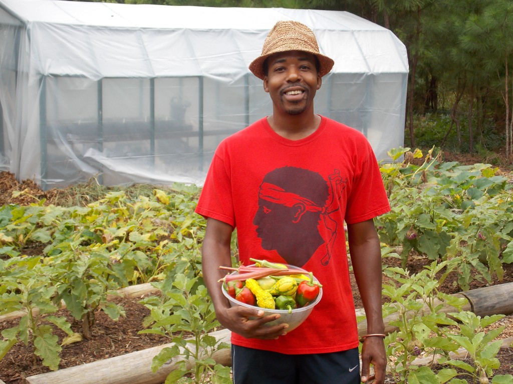 A man holding a basket of fresh vegetables in a garden.