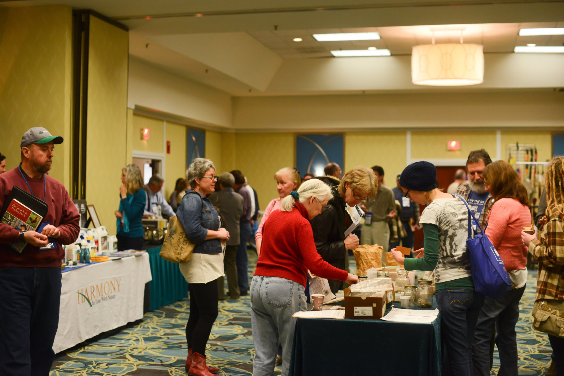 People interacting at an indoor market or fair with various products displayed.