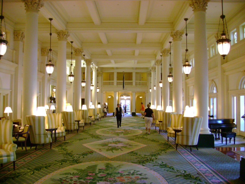 Elegant hallway with chandeliers and patterned carpet.