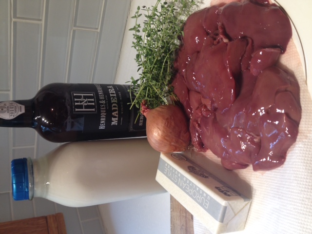 Raw liver with butter, onion, and herbs on a kitchen counter.