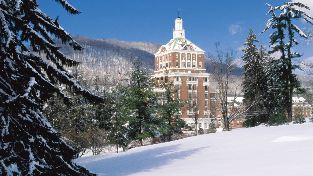 A large building surrounded by snow-covered trees and mountains.
