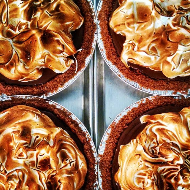 Four golden-brown meringue-topped pies in a metal tray.