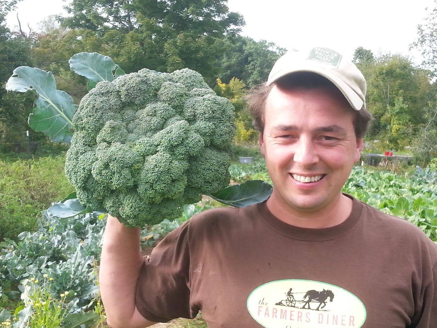 A man holding a large broccoli head.