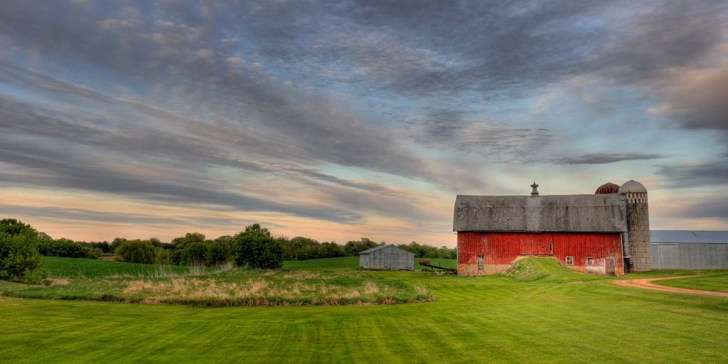 A red barn with a weather vane at sunset.