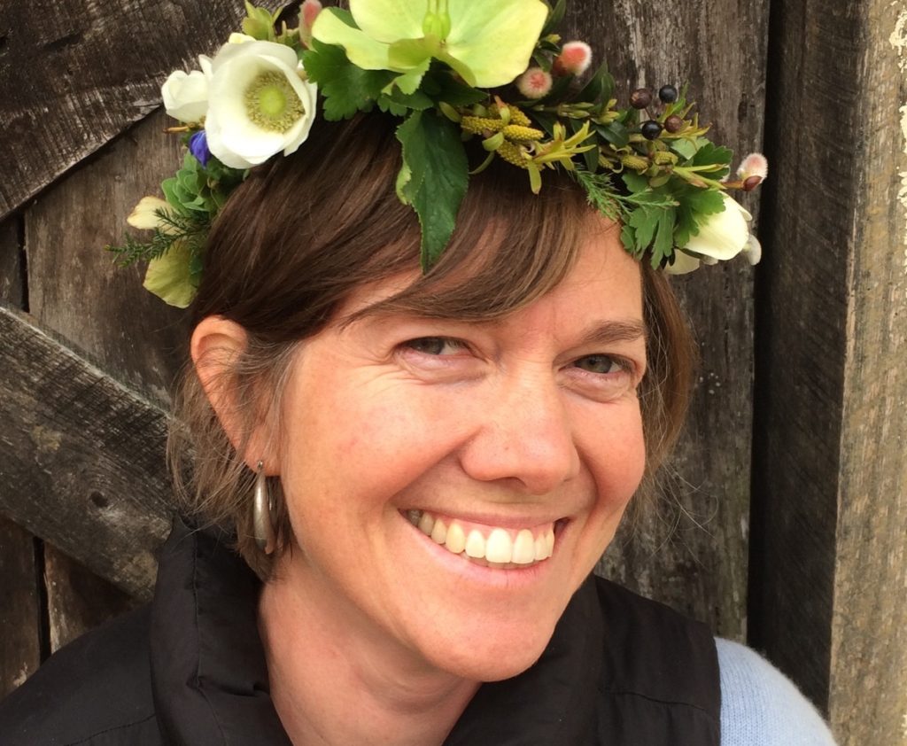 A smiling woman wearing a flower crown.
