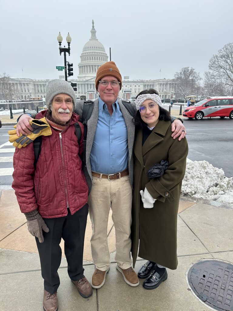 Three people standing together outdoors in winter clothing.