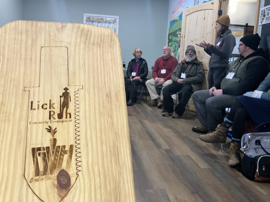 A wooden board with guitar-related drawings and a group discussion in the background.
