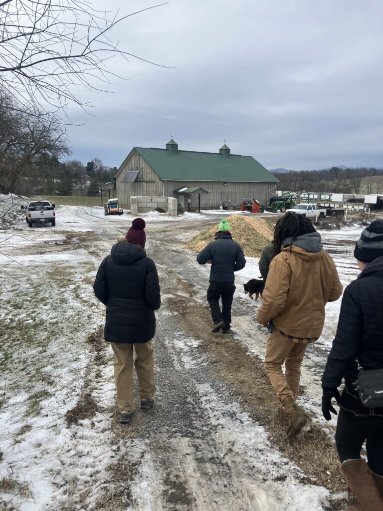 People walking on a snowy path toward a building in a rural area.