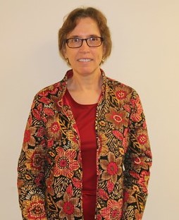 A woman wearing glasses and a floral patterned jacket.