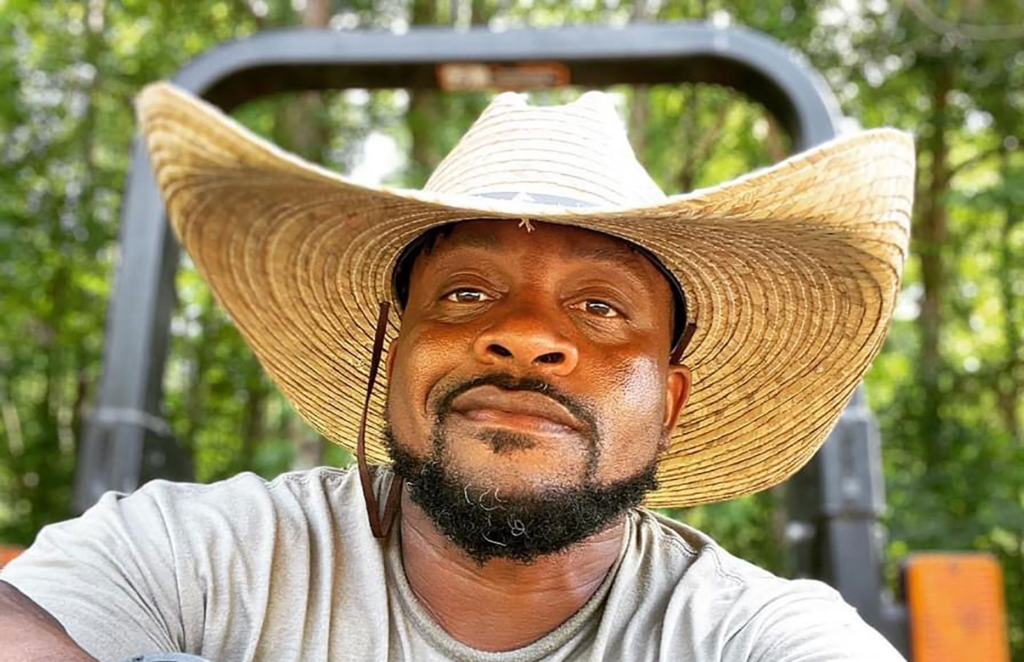 A man wearing a large straw hat outdoors.