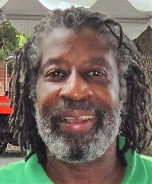 A man with dreadlocks and a beard smiling.