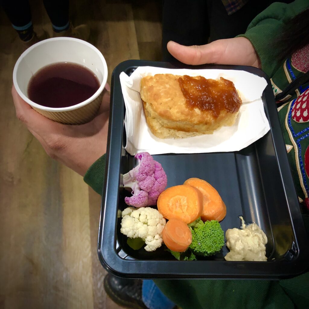 A bento box with tempura, rice, and colorful side dishes, plus a cup of tea.